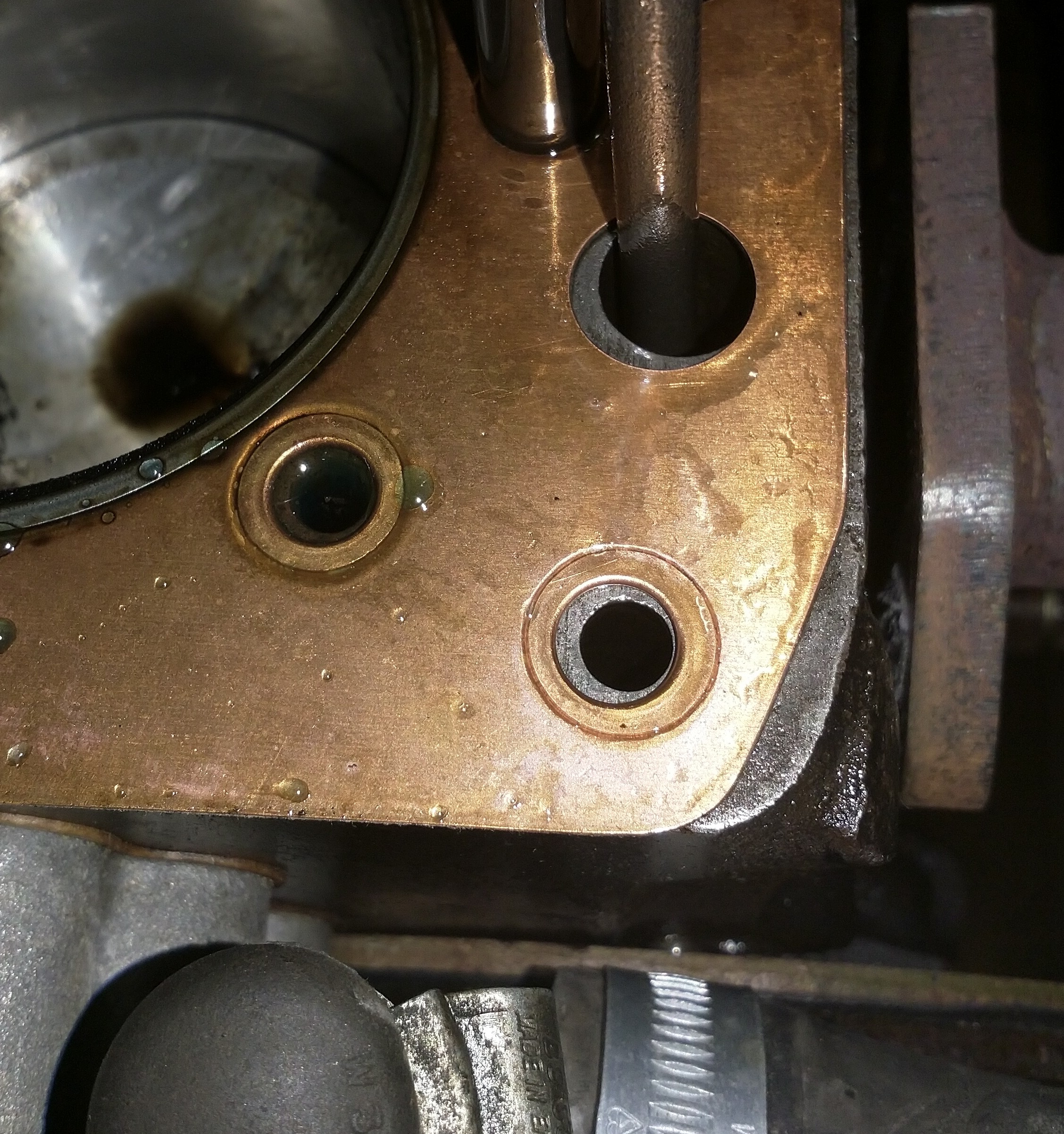 Head gasket still in place. It may have moved slightly as I removed the head. The oil & water is a small spillage from the head. The leak is at the bottom right edge.